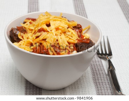 Bowl of pasta with sausage, corn, grated cheddar cheese and tomato sauce