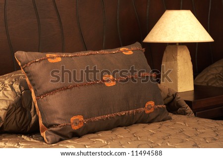 Colorful cushion on a bed with a bedside lamp next to it in a guest lodge