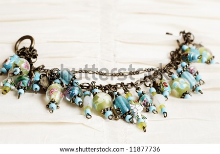 Fashionable colorful charm bracelet on cream linen background