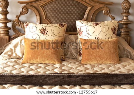Colorful cushions with luxurious duvet cover on a made up wooden bed in a guest lodge