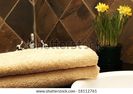 Modern bathroom interior with orange towels lying next to the sink and daffodil flowers