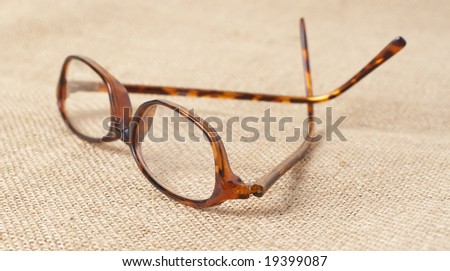 Brown horn-rimmed glasses on mesh material. Shallow depth of field