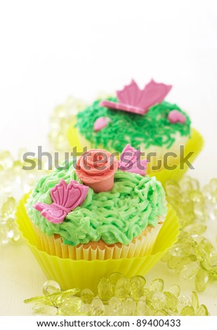Vanilla cupcakes with buttercream icing and various decorations on white background