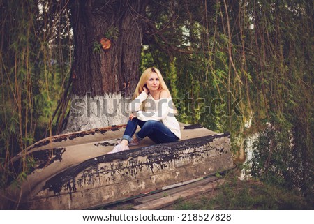 Young women with blond long hair seating on the old boat