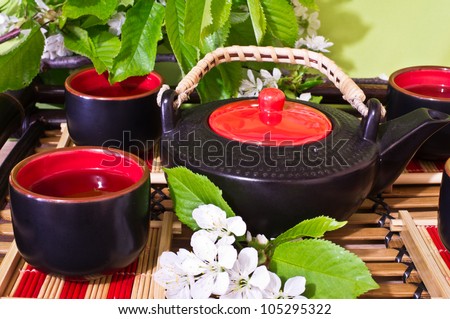 Green tea in a ceramic cup, ceramic teapot, chery