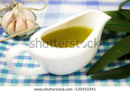 Olive oil in a gravy boat with garlic and olive leaves