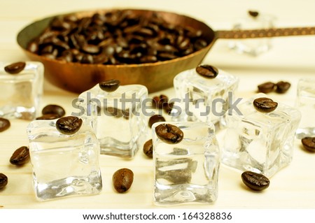 Pieces of ice with coffee beans. Background of coffee beans roasted in a pan.
