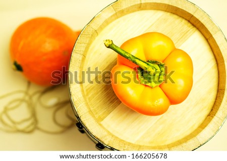 Orange sweet pepper on a wooden barrel. Orange vegetables on background not in focus.