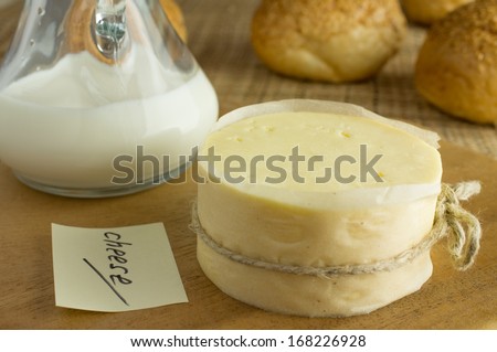 Head Cheese and milk bottle on a wooden table with a sticker cheese. Background bread.