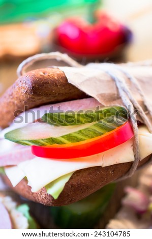 Sandwich with ham, cheese, lettuce and pickles in fast food packaging