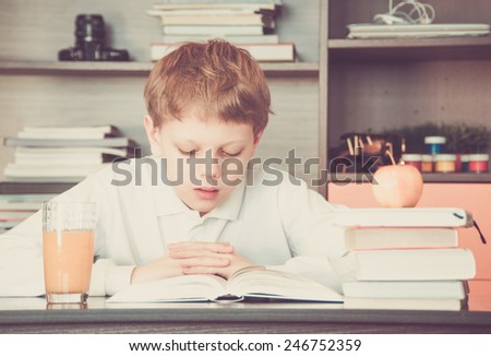 Boy reading a book and orange juice on the table
