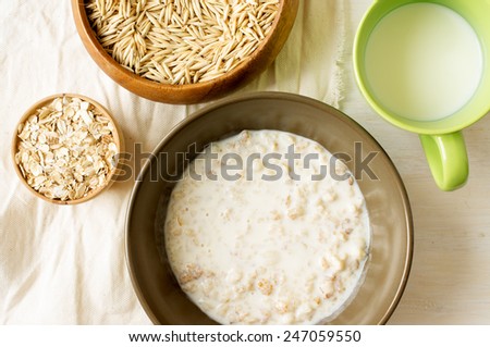 Oat milk porridge in a brown bowl on the table with oats