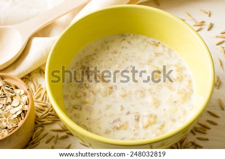 Oat milk porridge in a yellow bowl on the table with oats