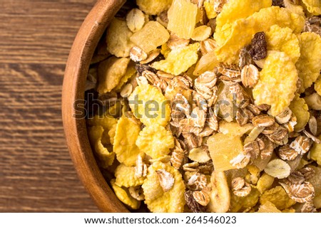 Breakfast cereals in wooden bowl closeup view from above