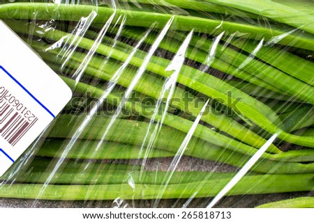 Packaging of fresh green onions with a price tag and bar code at the store on the market