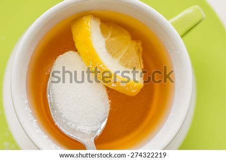 Spoon with sugar substitute, sorbitol dissolved in a cup of tea with lemon