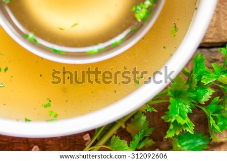Closeup of broth in a saucepan and ladle and parsley