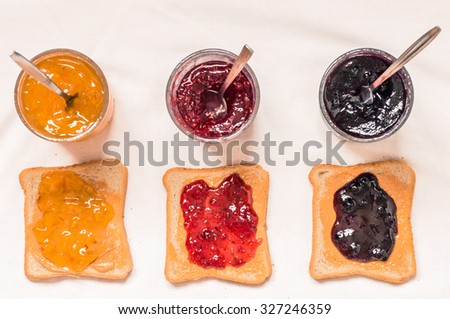Toast sandwiches with peanut butter and jam raspberry, blueberries, orange top view