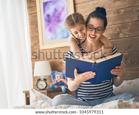 Pretty young mother reading a book to her daughter. Family holiday and togetherness.