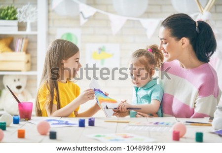 Happy family. Mother and daughters painting together. Adult woman helping to child girl.