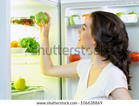 a hungry girl opens the fridge