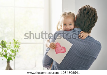 Happy father\'s day! Child daughter congratulating dad and giving him postcard. Daddy and girl smiling and hugging. Family holiday and togetherness.