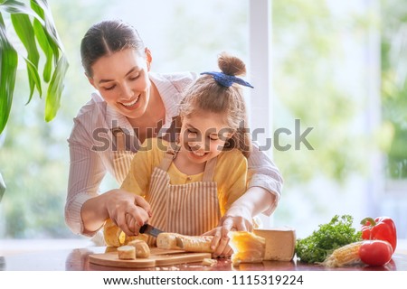 Family breakfast. Mother and her child daughter cut bread and cheese in morning.