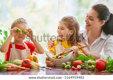 Healthy food at home. Happy family in the kitchen. Mother and children daughters are preparing the vegetables.