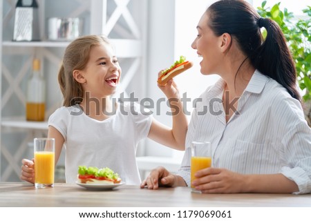 Healthy food at home. Happy family in the kitchen. Mother and child daughter are having breakfast.
