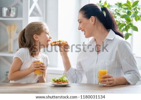 Healthy food at home. Happy family in the kitchen. Mother and child daughter are having breakfast.