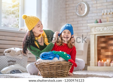 Winter portrait of happy loving family wearing knitted sweaters. Mother and child girl having fun, playing and laughing at home. Fashion concept.