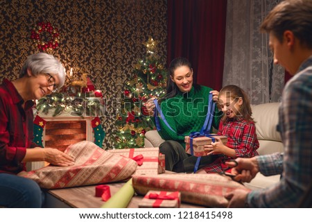 Merry Christmas and Happy New Year! Grandma, mum, dad and daughter near the tree at home. Family preparing for Holiday.