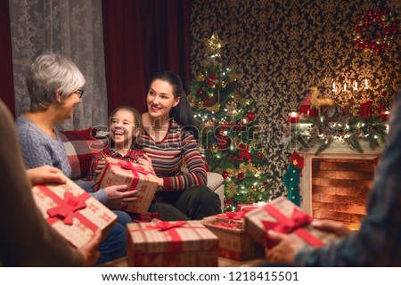 Merry Christmas and Happy Holidays! Grandma, grandpa, mum, dad and child exchanging gifts. Parents and daughter having fun near tree indoors. Loving family with presents in room.