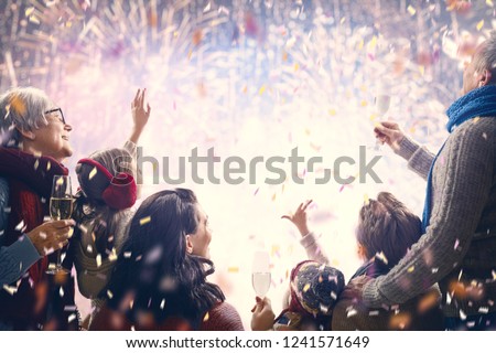 New Year holiday. Parents and daughters children girls are watching fireworks. Happy family on snowy winter walk in nature. Holidays winter season.