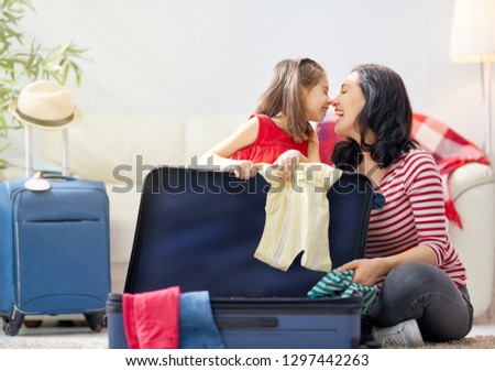 Go on an adventure! Happy family preparing for the journey. Mom and daughter are packing suitcases for the trip.