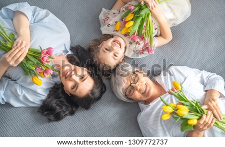 Happy women\'s day! Child, mom and granny with flowers tulips. Grandma, mum and girl smiling. Family holiday and togetherness.