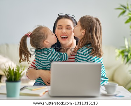Young mother with children working on the computer from home. Happy family enjoying success.