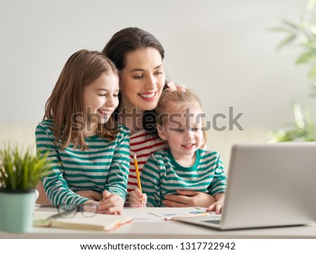 Young mother with children working on the computer from home. Happy family enjoying success.