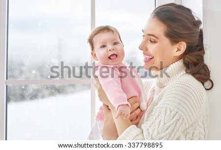 Happy cheerful family. Mother and baby hugging near window.