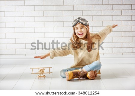happy child girl playing with toy airplane. the dream of becoming a pilot