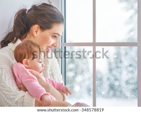 Happy cheerful family. Mother and baby hugging near window.