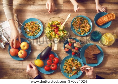 Top view of family having dinner together sitting at the rustic wooden table. Enjoying  family dinner together.
