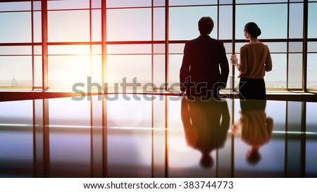 team of successful business people. two businessmen resting and talking in the office. man and woman look at the city from the window of the business center.