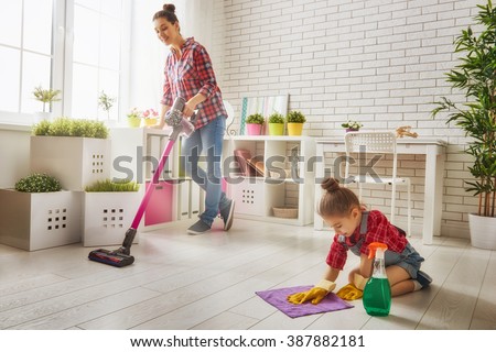 Happy family cleans the room. Mother and daughter do the cleaning in the house. A young woman and a little child girl wiped the dust and vacuumed the floor.