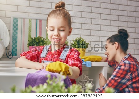 Happy family cleans the room. Mother and daughter do the cleaning in the house. A young woman and a little child girl dusting.