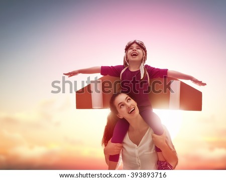 Mother and her child playing together. Little child girl plays astronaut. Child in an astronaut costume plays and dreams of becoming a spaceman. Happy loving family having fun.