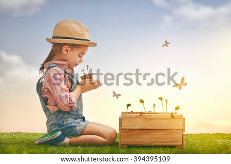Cute little child girl planting seedlings. Fun little gardener. Spring concept, nature and care.