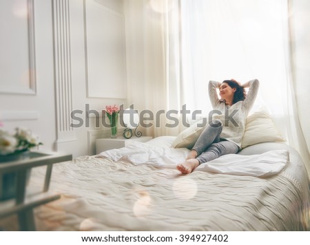 Happy young woman enjoying sunny morning on the bed