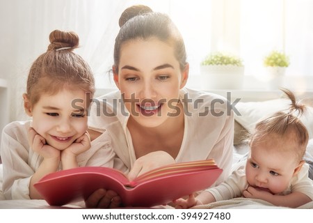 happy loving family. pretty young mother reading a book to her daughters