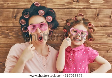 Funny family! Mother and her child daughter girl with a paper accessories. Beauty funny girl holding paper glasses on stick. Beautiful young woman holding paper glasses on stick.